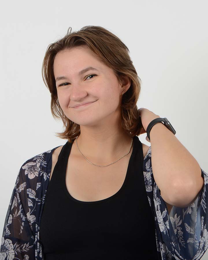 Portrait of Chloe wearing a black tank top. She has short brown hair.